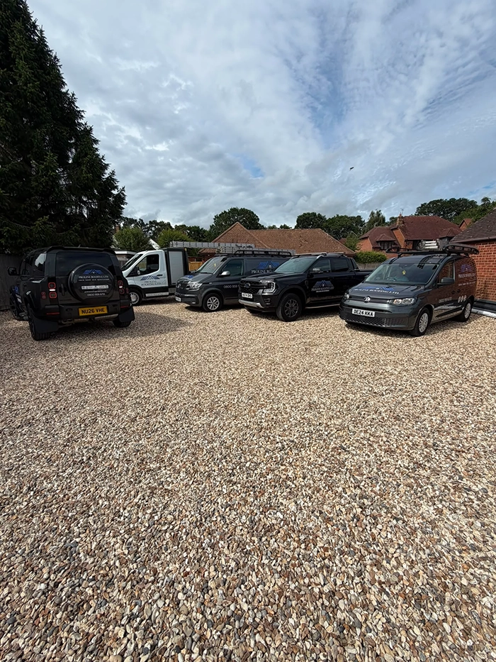 Five branded Proline Roofing vehicles parked on gravel in front of houses under a cloudy sky.