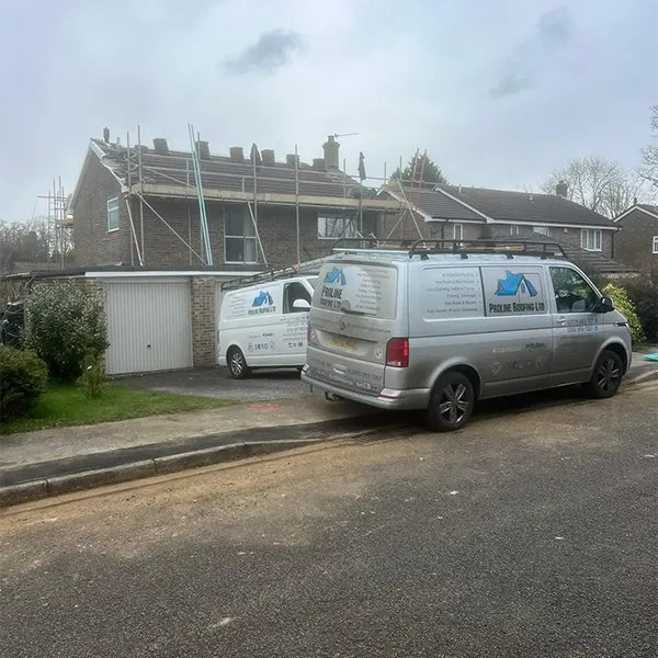 Two vans parked in front of a house under construction.