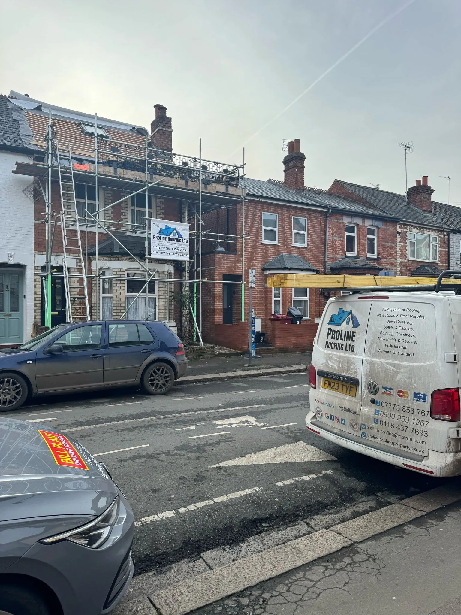 A white van driving down a street next to tall buildings.